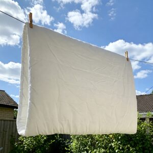 Illustration of a mattress topper being air-dried outdoors after following instructions on how to clean a mattress topper.