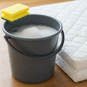 Illustration showing the cleaning solution and tools for washing a mattress topper, a key step in how to clean a mattress topper.