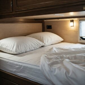 "Camper bunk mattress shown with cozy bedding, including sheets and pillows."