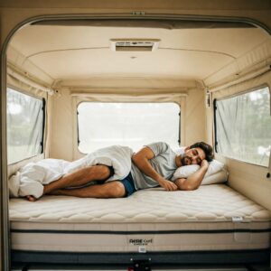 Person sleeping comfortably on a pop up trailer mattress.