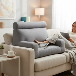 Blue reading pillow with arm support placed on a living room couch for versatile lounging.